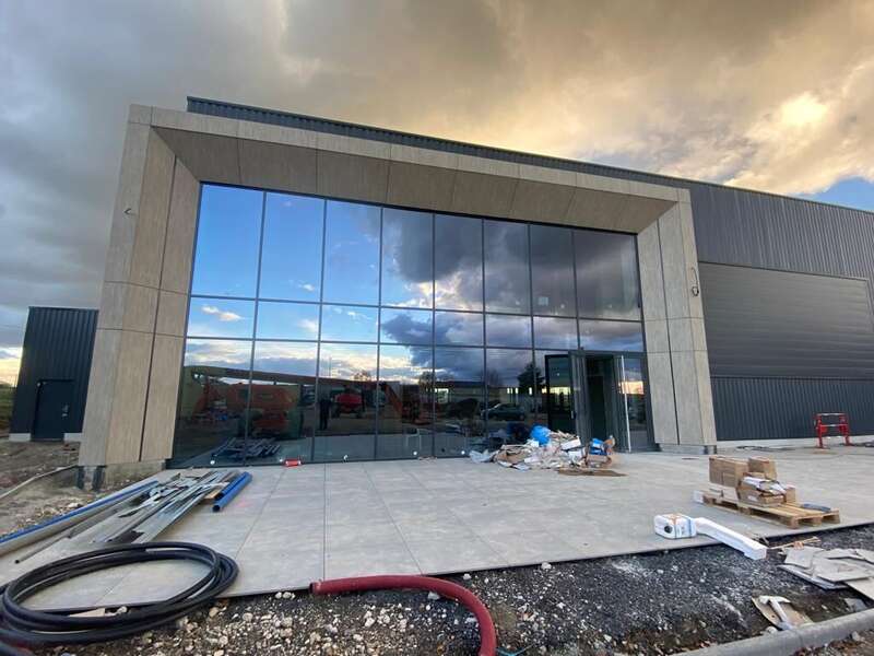 Bâtiment tertiaire neuf : grande façade vitrée encadrée de panneaux composites et de bardage métallique