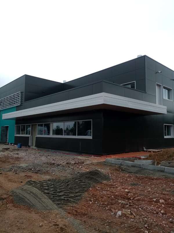 Bâtiment en panneaux composites gris anthracite avec auvent