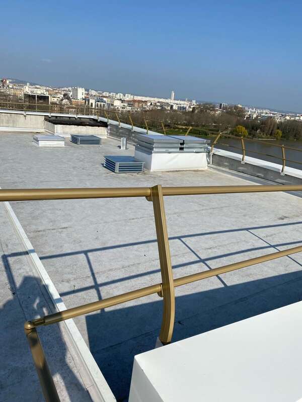 Garde-corps en aluminium thermolaqué doré en bord de toiture-terrasse, avec vue sur la Seine